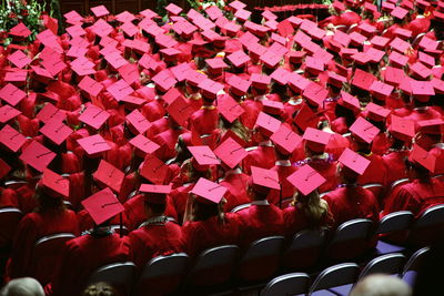 High angle view of students in graduation gown sitting on chairs