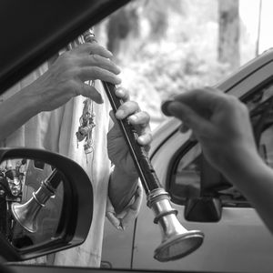 Cropped image of hand giving coin to beggar playing shehnai