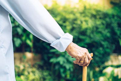 Midsection of person holding walking cane