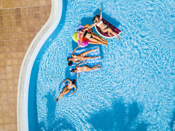Drone view of women relaxing in swimming pool