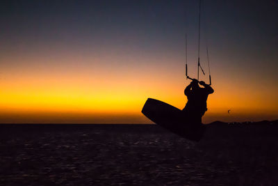 Silhouette person in sea against sky during sunset