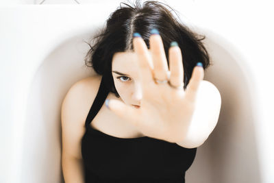 Close-up portrait girl gesturing while sitting in bathtub