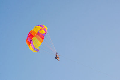 Low angle view of person parasailing against blue sky