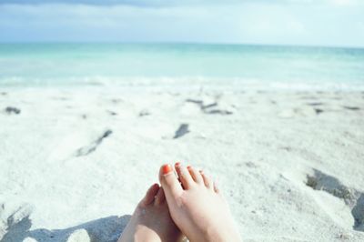 Low section of woman at beach on sunny day