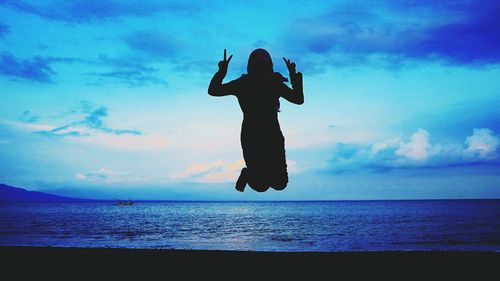 Silhouette woman on beach against sky