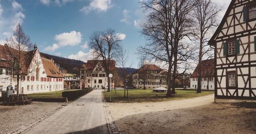 Empty road amidst buildings against sky on sunny day at blaubeuren