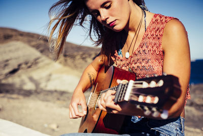 Young woman playing guitar at beach