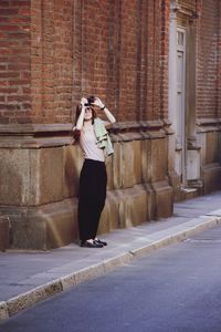 Full length of woman standing against wall