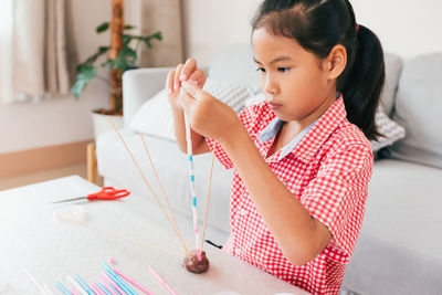 Cute asian child girl playing and creating with play dough and straws. 