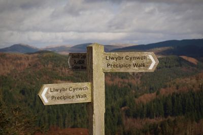 Information sign on mountain against sky