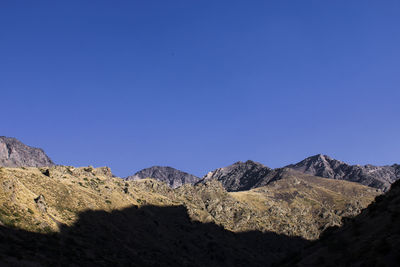 View of rocky mountains against clear blue sky