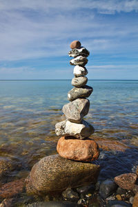 Stack of stones on rock against blue sky