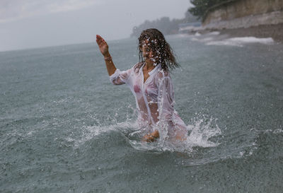 Midsection of woman splashing water in sea