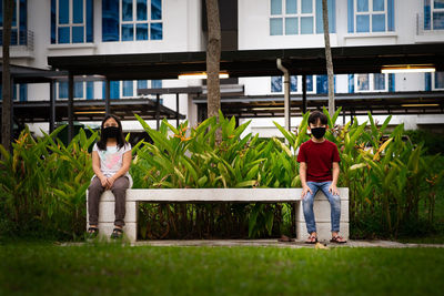 Rear view of couple sitting on sidewalk