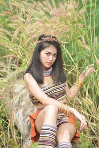 Portrait of a beautiful young woman sitting on field