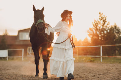 Rear view of woman riding horse on field