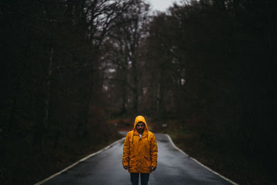 Man standing on road amidst trees in forest