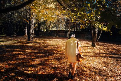 Rear view of woman walking in park during autumn