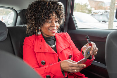 Pretty african american woman in car doing makeup while standing in a traffic
