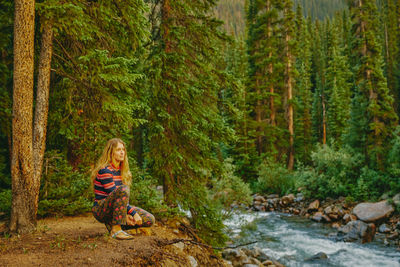 Young woman sitting on riverbed during sunset sunset near aspen