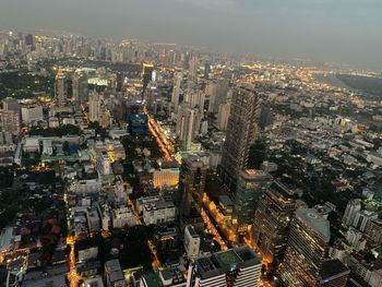 Aerial view of illuminated buildings in city against sky