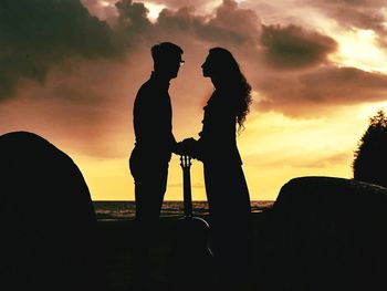 Silhouette couple standing against sky during sunset