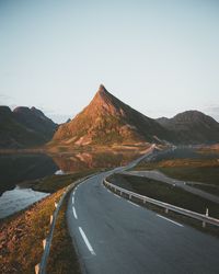 Road leading towards mountain against clear sky