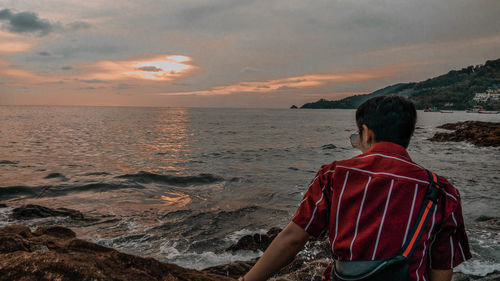 Rear view of man looking at sea against sky