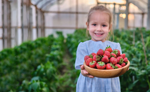 Portrait of cute girl holding strawberries