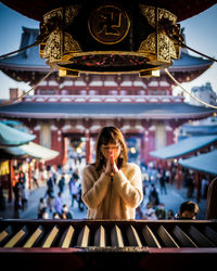 Portrait of woman standing against illuminated traditional building