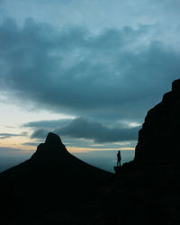 Silhouette people standing on rock against sky