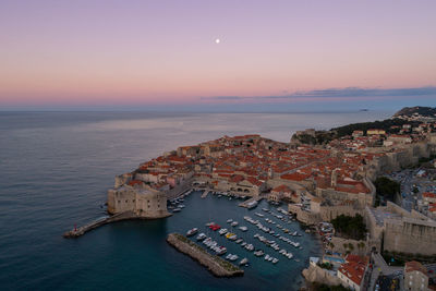 High angle view of townscape by sea against sky during sunset