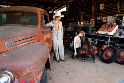 Rusty car and mannequins in garage