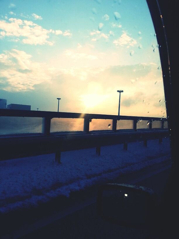 sky, sunset, snow, transportation, cloud - sky, winter, cold temperature, sun, silhouette, sunlight, built structure, mode of transport, nature, cloud, architecture, car, weather, no people, land vehicle, railing