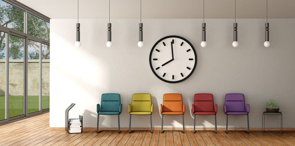 Clock above empty colorful chairs in office