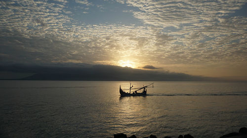 Silhouette boat in sea against sky during sunset