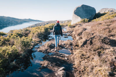 Rear view of man walking on mountain against clear sky