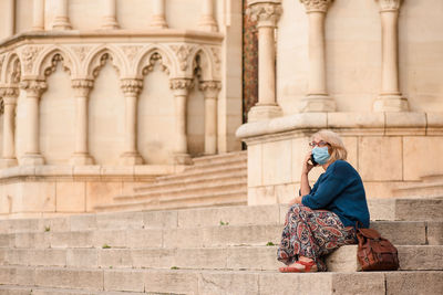 Full length of woman sitting outside building