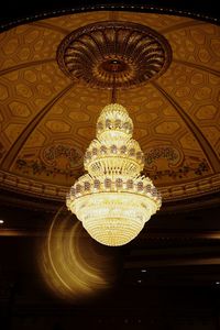 Low angle view of illuminated chandelier hanging on ceiling