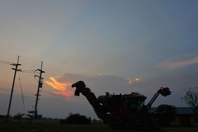 Silhouette cranes against sky during sunset