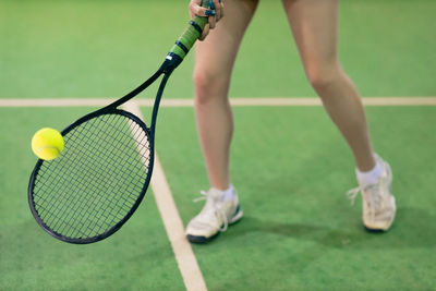 Low section of tennis player playing at court