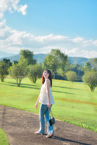 Rear view of woman walking on field against sky