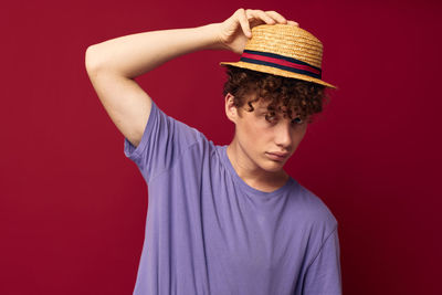 Portrait of young woman wearing hat against yellow background