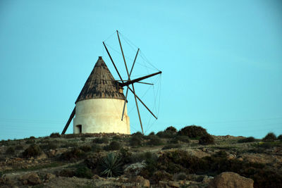 Traditional windmill on field against clear sky