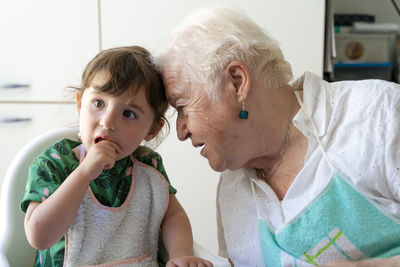 Grandmother and granddaughter resting their heads with love