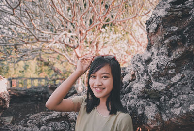 Portrait of a smiling young woman standing against plants