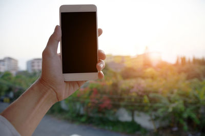 Close-up of hand holding smart phone against clear sky