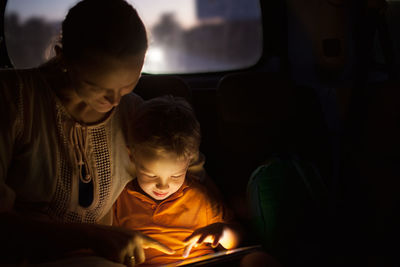 Mother and son using digital tablet while siting in car