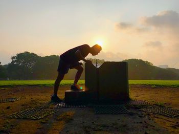 Man standing on field against sky during sunset