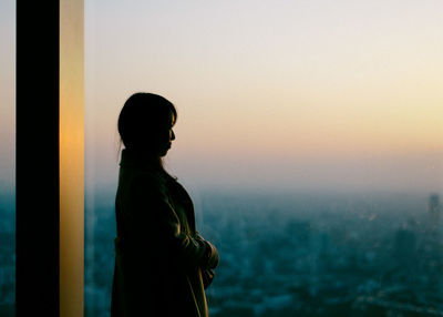 Woman standing against sky during sunset